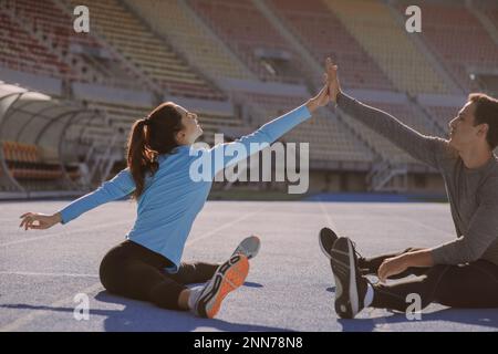 Due amici graziosi si stanno dando a vicenda cinque alti mentre allungano i loro corpi Foto Stock