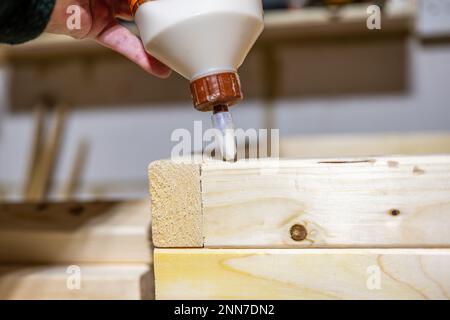 applicazione di colla per legno sul giunto del letto di una scatola piantatrice per legname in officina Foto Stock