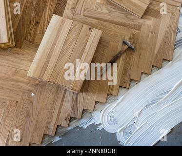 Vista dall'alto di pannelli in parquet che si installano in una disposizione a spina di pesce su colla, concetto di pavimentazione domestica Foto Stock