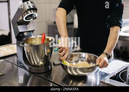 Lo chef lavora in cucina. Il processo di preparazione dell'impasto per macaroni. Foto Stock