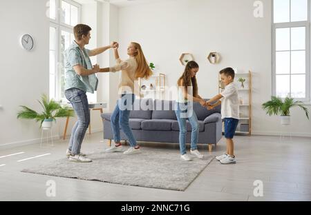 Felice famiglia caucasica con due figli, piccolo figlio e figlia, che ballano insieme a casa. Foto Stock