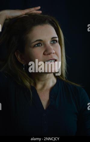 ritratto di una bella donna bionda che tiene la mano sopra la testa ed esasperata con troppo lavoro Foto Stock