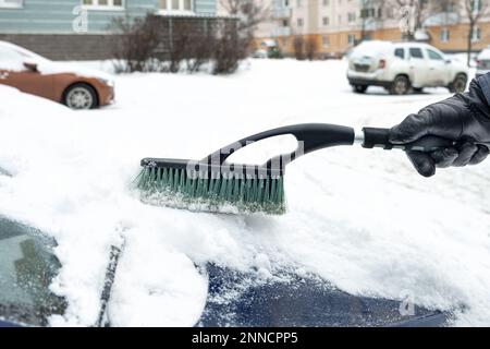 La mano di un uomo in un guanto pennellerà il cappuccio della sua auto Foto Stock