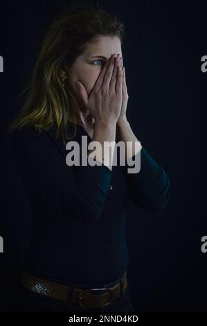 il ritratto di una bella donna bionda stanca copre il suo volto con entrambe le mani Foto Stock