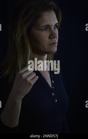 ritratto di una bella donna bionda che gioca con i suoi capelli mentre nel profondo del pensiero Foto Stock