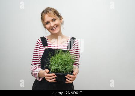 Una donna sta tenendo un micro verde nelle sue mani. Primo piano. Foto Stock