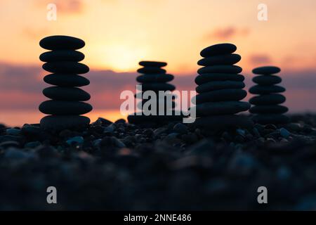 Profilo equilibrato piramidale di ciottoli sulla spiaggia al tramonto con Mare sullo sfondo. Pietre Zen sulla spiaggia di mare, meditazione, spa, armonia, calma, Foto Stock