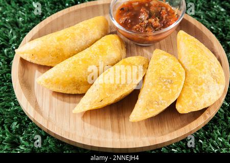 Gustoso cibo colombiano, empanada fritto; foto su sfondo di legno. Foto Stock