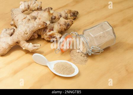 Radici fresche e polvere di zenzero - Zingiber officinale; foto su sfondo ligneo. Foto Stock