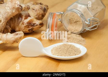 Radici fresche e polvere di zenzero - Zingiber officinale; foto su sfondo ligneo. Foto Stock