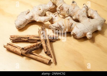 Radice di zenzero con cannella; su fondo di legno. Foto Stock