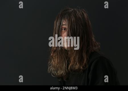 Ritratto dell'uomo di mezza età con capelli lunghi su sfondo nero Foto Stock