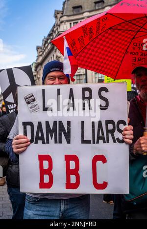 Uomo con il cartello 'Liars, Damn Liars BBC e la bandiera russa in testa, Campagna per il disarmo nucleare (CND) e il manifesto della coalizione Stop the War Foto Stock