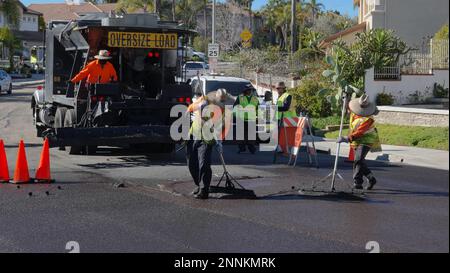 Vista, CA USA - Febbraio 6 2023: Un equipaggio di lavoratori applica la foca di liquame a una strada residenziale Foto Stock