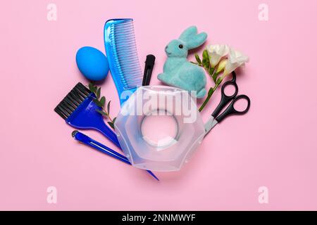 Accessori per parrucchieri con uovo di Pasqua, coniglio e fiori su sfondo rosa Foto Stock