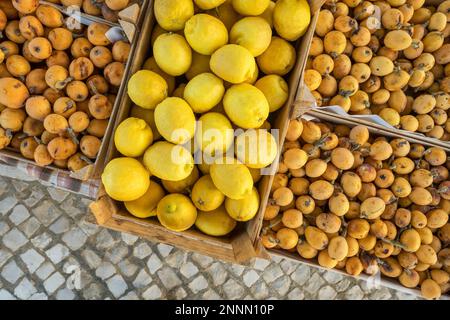 Limoni e loquat frutta in scatole di legno sul mercato agricolo in Portogallo Foto Stock