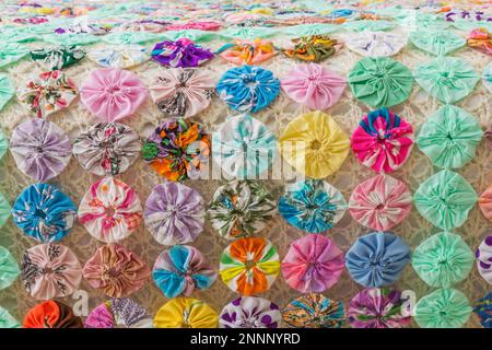 Primo piano di colorati motivi floreali copriletto trapuntato sul letto queen size nella camera da letto degli ospiti al piano superiore all'interno di una casa contemporanea. Foto Stock