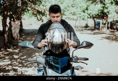 Uomo in moto che indossa il casco. Motociclista mettere su casco di sicurezza, Biker moto concetto di sicurezza. Giovane uomo motociclista che mette in sicurezza Foto Stock