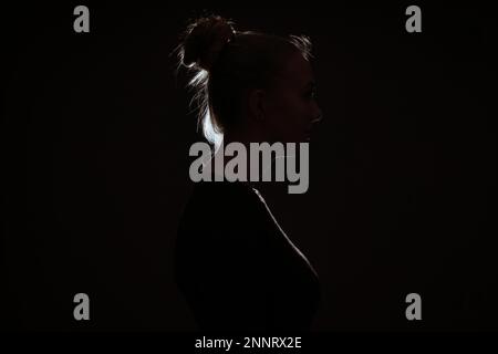 Vista profle di donna nascosti nel buio per preservare l'anonimato - contorno Retroilluminato con luce di RIM Foto Stock