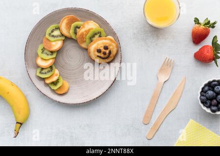 Frittelle fatte in casa a forma di bruco, servite con frutta. Foto Stock