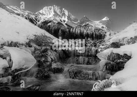 Sulfur Creek scorre attraverso il paesaggio di montagna ghiacciato in bianco e nero, Canmore, Alberta, Canada Foto Stock