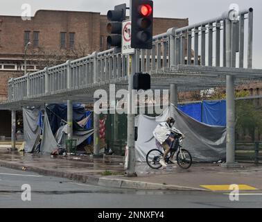 Un uomo senza casa guida la sua bicicletta davanti a un accampamento senza casa sulla superstrada 101 durante una pausa dalla pioggia a Los Angeles, California, sabato 25 febbraio. 2023. Alcune parti della California sono rimaste sotto i severi avvertimenti invernali per un secondo giorno il sabato, mentre i funzionari statali hanno continuato a scoraggiare il viaggio per la durata del fine settimana. Le avvertenze Blizzard sono in vigore anche durante la domenica nella Sierra Nevada centrale e meridionale e nelle catene montuose trasversali e peninsulari. L'ultima volta che l'ufficio di Los Angeles del servizio ha emesso un avvertimento blizzard era 1989. Foto di Jim Ruymen/UPI Foto Stock