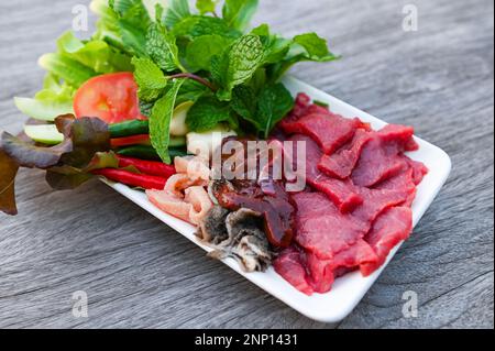 carne di manzo cruda taglia fette su piatto bianco e verdure fresche carne fresca vista dall'alto - sashimi di manzo, fegato di manzo cibo asiatico tailandese Foto Stock