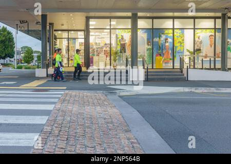 Tauranga Nuova Zelanda Febbraio 21 2023; tre operai in giubbotti di flouro sfocato camminare al lavoro accanto vetrine colorate grande magazzino sulla città s Foto Stock