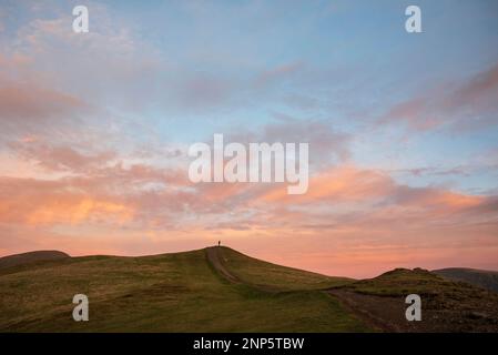 Il bellissimo paesaggio del tramonto invernale sopra Latrigg è caduto nel Lake District con un unico perosn sulla cima della collina ammirando il tramonto Foto Stock