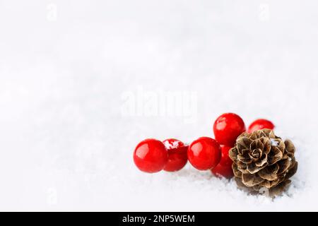 Composizione natalizia di coni e rami di bacche rosse isolate su fondo innevato bianco. Natale, concetto di Capodanno. primo piano. Copia Foto Stock