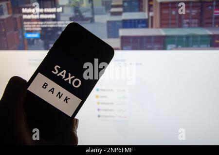 Rheinbach, Germania 26 febbraio 2023, il logo del marchio danese on-line ha rotto 'Saxo Bank' sul display di uno smartphone di fronte al sito web Foto Stock