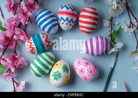 Vivace e allegro piatto sfondo presenta un cerchio di colorate uova di Pasqua adornato con decorazioni festive, circondato da fiori di primavera e b Foto Stock