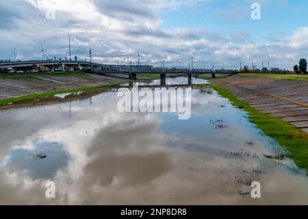 L'area industriale e la ferrovia si riflettono nell'acqua del canale di versamento a Pontedera, Pisa, Italia Foto Stock