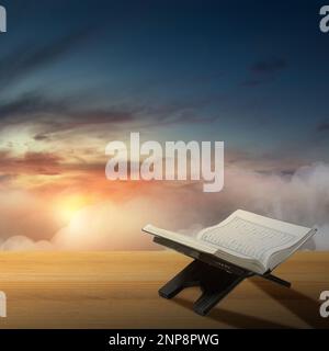 Aperto Quran su un placemat di legno sulla tavola di legno con un suggestivo sfondo cielo Foto Stock