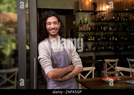 Portrait of young adult local small business owner looking at camera. Cheerful bar worker smiles. Foto Stock