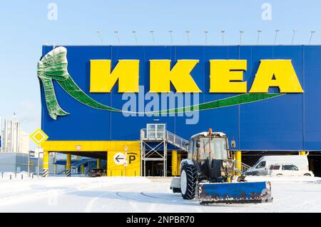 L'iscrizione sul negozio 'IKEA', con decorazioni natalizie accanto al trattore e neve più pulita il parcheggio in inverno Foto Stock