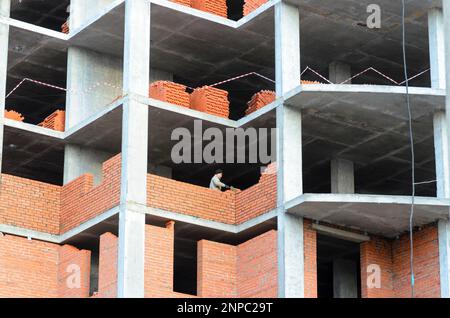 Due costruttori posano muri in mattoni in una nuova casa multi-appartamento in costruzione in Russia. Foto Stock