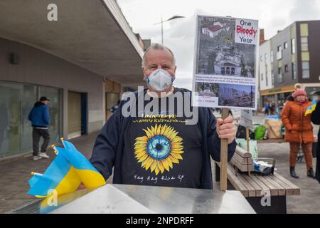 Southend on Sea, Regno Unito. 26 febbraio 2023. Un uomo ha un cartello con la scritta "un anno di sangue" e bandiere ucraine durante una protesta pubblica a Southend-on-Sea, a un anno dall'invasione russa dell'Ucraina. Altri dimostranti sono visibili nell'abbigliamento invernale, mostrando sostegno attraverso bandiere e cartelli. Insieme a Southend tengono la loro veglia settimanale nella High Street per mostrare sostegno e sottolineare la situazione in Ucraina. Penelope Barritt/Alamy Live News Foto Stock