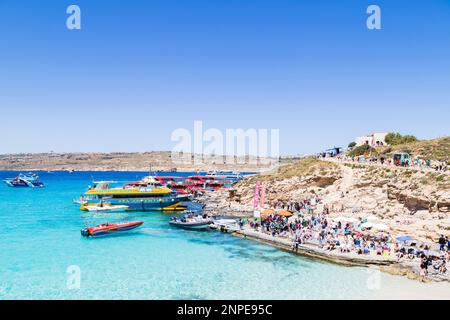 I turisti sulle rive della Laguna Blu sull'Isola di Comino imbarcano e sbarcano vari tipi di barche. Foto Stock