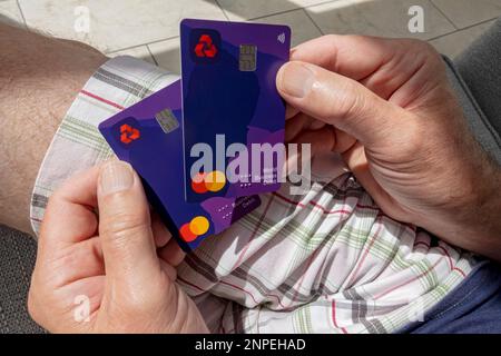 Primo piano di un uomo in possesso della carta di debito contactless Business della banca Natwest. Foto Stock
