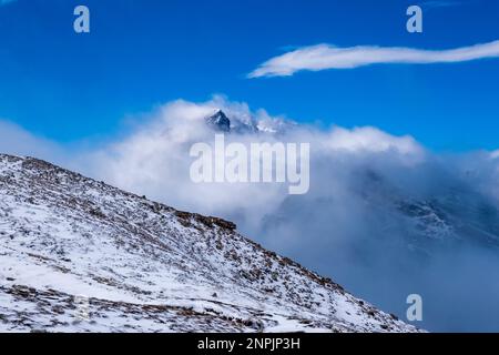 Le cime rocciose del Monte Cristallo, parzialmente avvolte da nuvole, ricoperte di neve fresca. Foto Stock