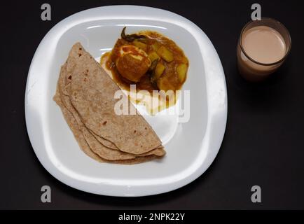 Colazione indiana Chappathi, arrosto alle uova e tè su sfondo nero Foto Stock