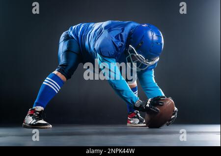 Il giocatore di calcio americano è pronto per iniziare la partita su sfondo nero. Foto Stock
