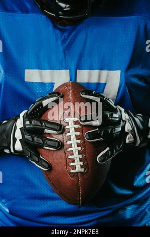 Primo piano di una palla di calcio americana nelle mani di un giocatore. Foto Stock