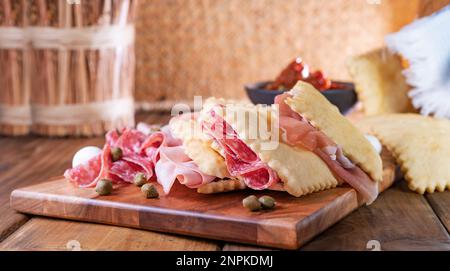 Crescentina. Cibo dell'Emilia Romagna, gnocco fritto o crescentina. Antipasto o aperitivo in Italia. Creshantina con prosciutto crudo, mortadella, salame milanese, capperi, formaggio Foto Stock