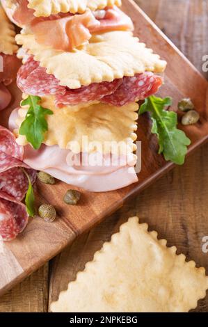 Crescentina. Cibo dell'Emilia Romagna, gnocco fritto o crescentina. Antipasto o aperitivo in Italia. Creshantina con prosciutto crudo, mortadella, salame milanese, capperi, formaggio Foto Stock