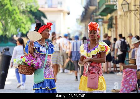 Le donne cubane in abiti tradizionali chiamati 'Costumbrista' mostrano i tempi coloniali sulla strada dell'Avana Vecchia su una folla di persone sullo sfondo Foto Stock