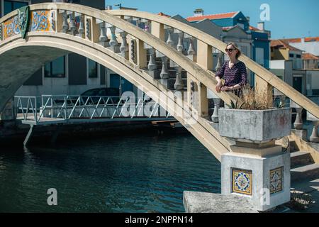 Una donna si trova vicino al ponte sui canali di Ria de Aveiro. Portogallo. Foto Stock