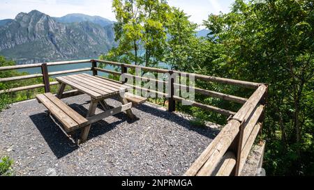 Tavolo da picnic in legno e due panchine sulla riva del lago. Foto Stock