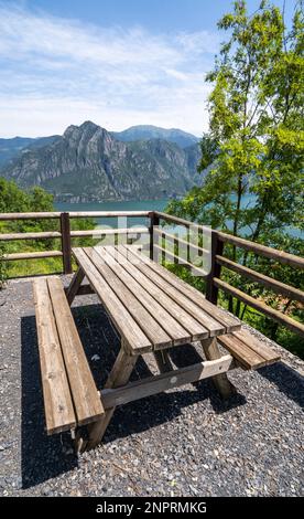 Tavolo da picnic in legno e due panchine sulla riva del lago. Foto Stock